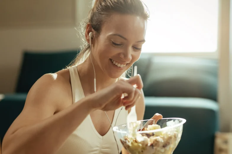 Happy athletic woman eating salad
