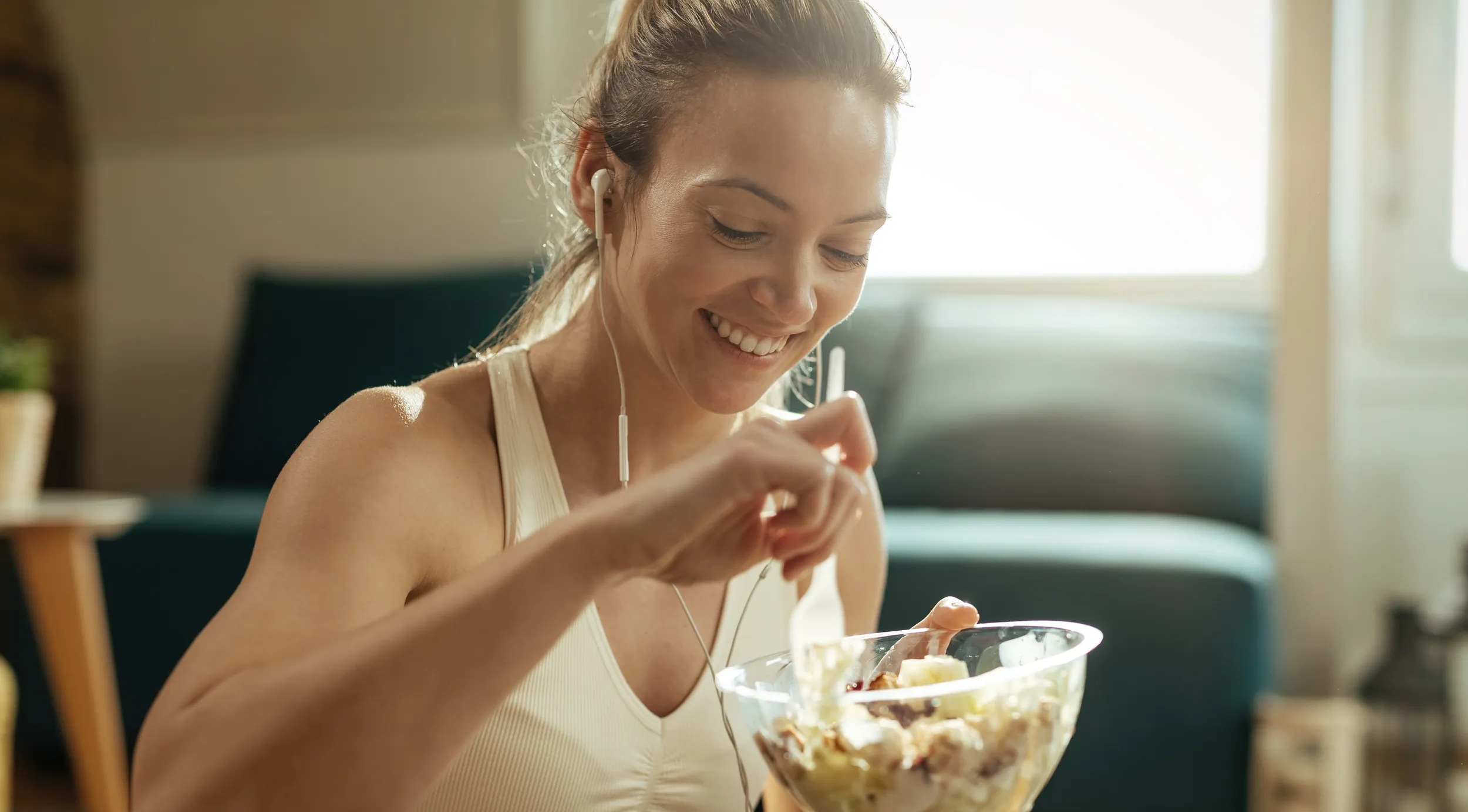 Happy athletic woman eating salad