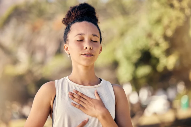 Woman practicing the grief point exercise with a hand resting gently over her heart.