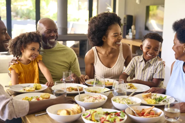 Multi-generational family gathered around a dining table, sharing a relaxed meal together in a calm, welcoming home environment.