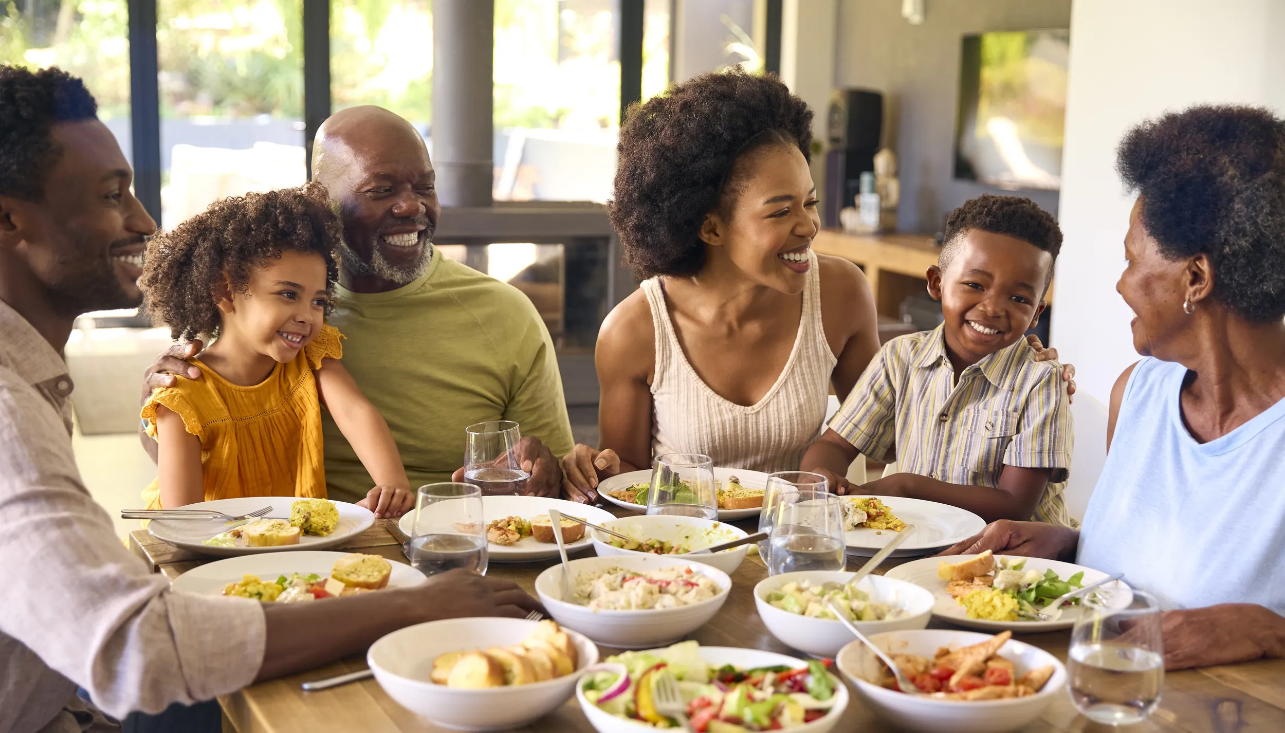Multi-generational family gathered around a dining table, sharing a relaxed meal together in a calm, welcoming home environment.
